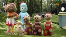 Six plush characters standing in a park.